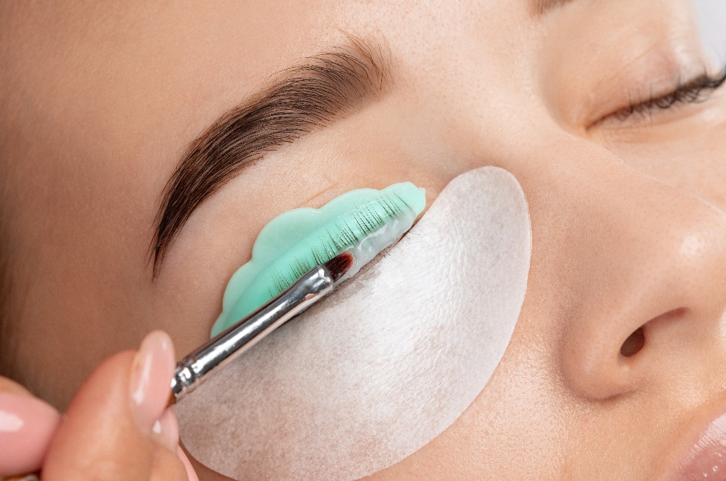 Ein Maskenbildner führt bei einer schönen Frau in einem Schönheitssalon die Prozedur der Laminierung und Färbung der Wimpern durch. Wimpernverlängerung. Wimpernlifting