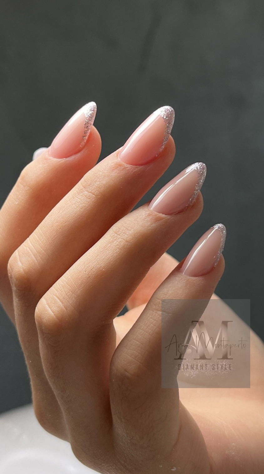 Eine Hand mit gepflegten, rosafarbenen Nägeln und glitzerndem Rand.