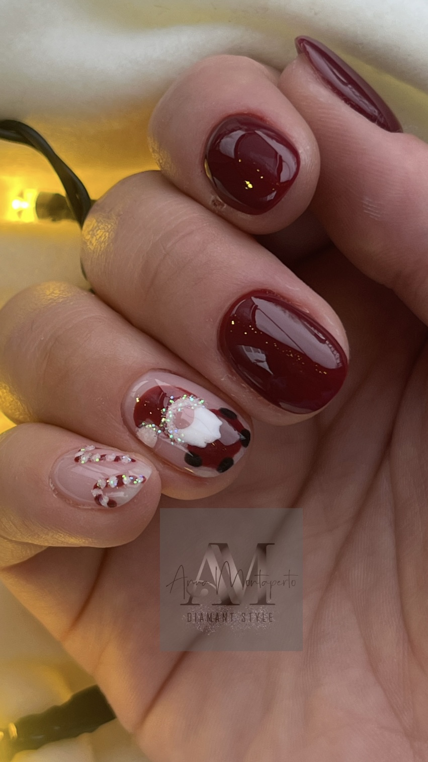 Rote und gemusterte manicure Nägel einer Hand mit verzierten Designs.