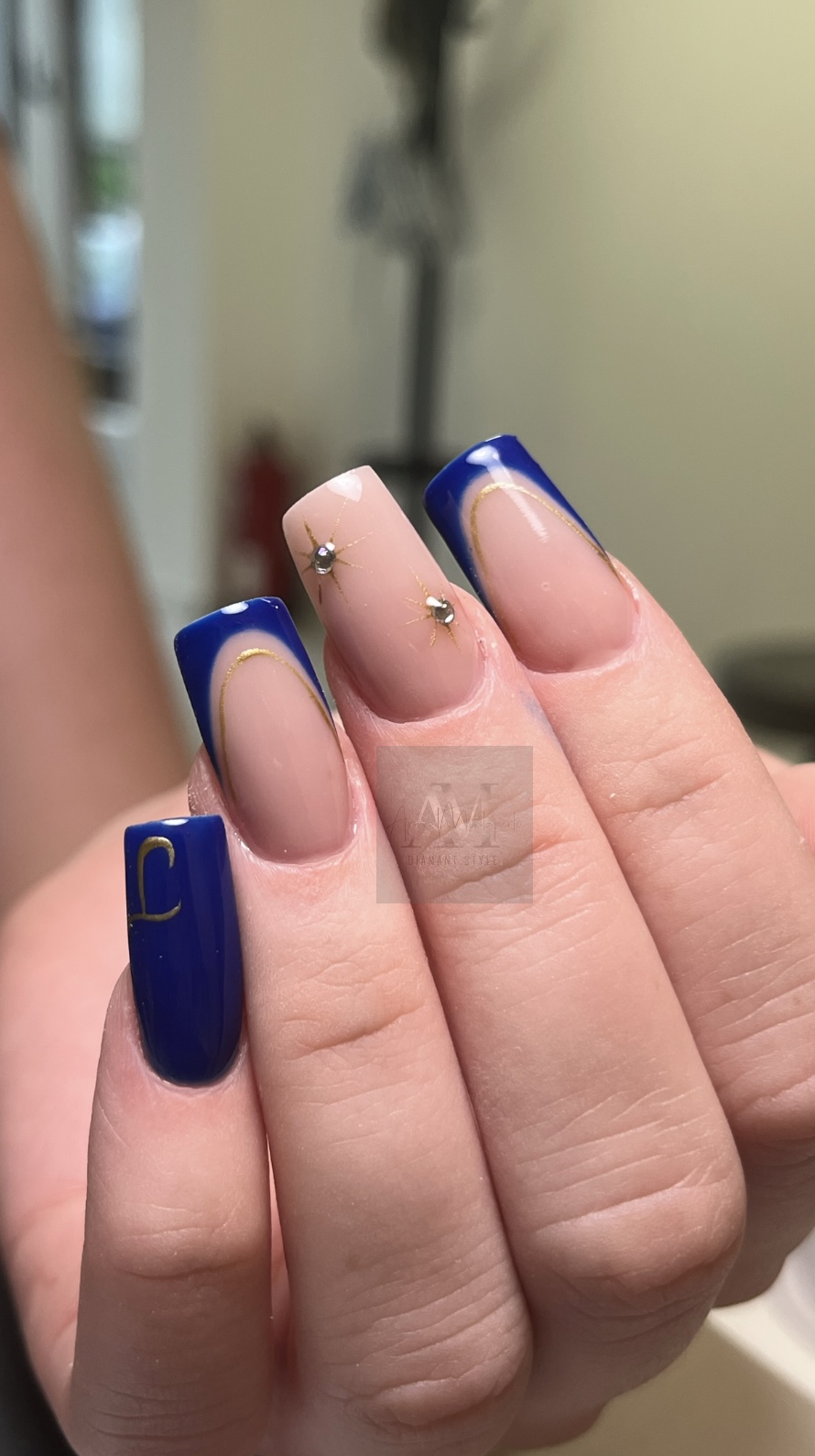 Eine Hand mit blauem Nageldesign und goldenen Sternakzenten