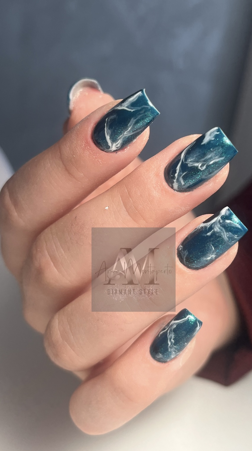 Nahaufnahme einer Hand mit türkis-weißem Marmormuster auf den Nägeln, einzigartig gestaltet.