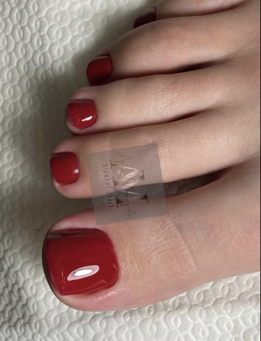 Nahaufnahme von Zehen mit glänzend rotem Nagellack auf einem weißen Handtuch