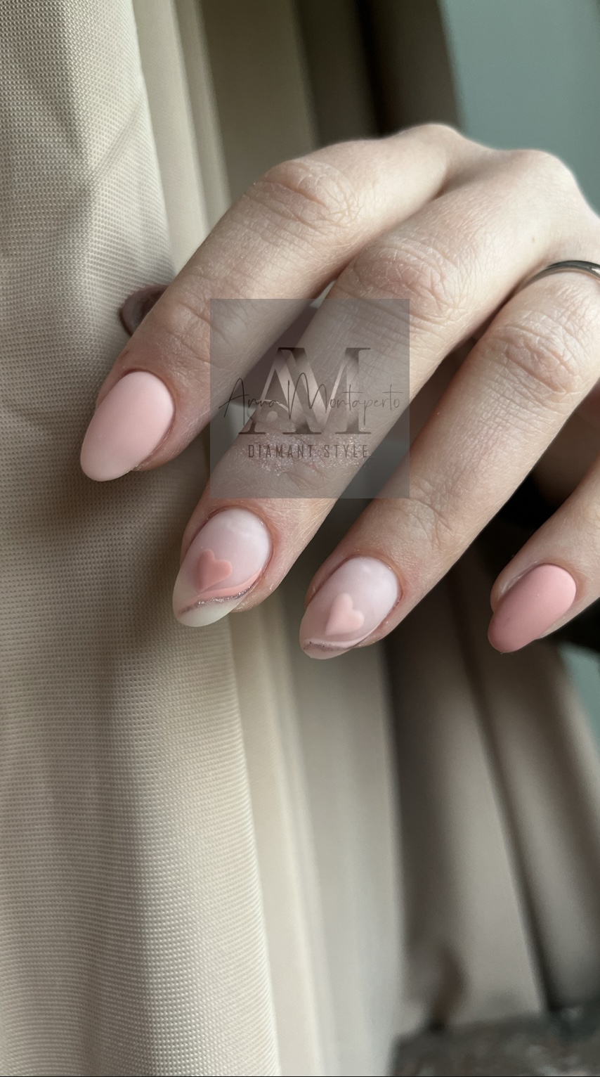 Eine Hand mit langen, rosafarbenen, mandelförmigen Nägeln und Herzverzierungen.