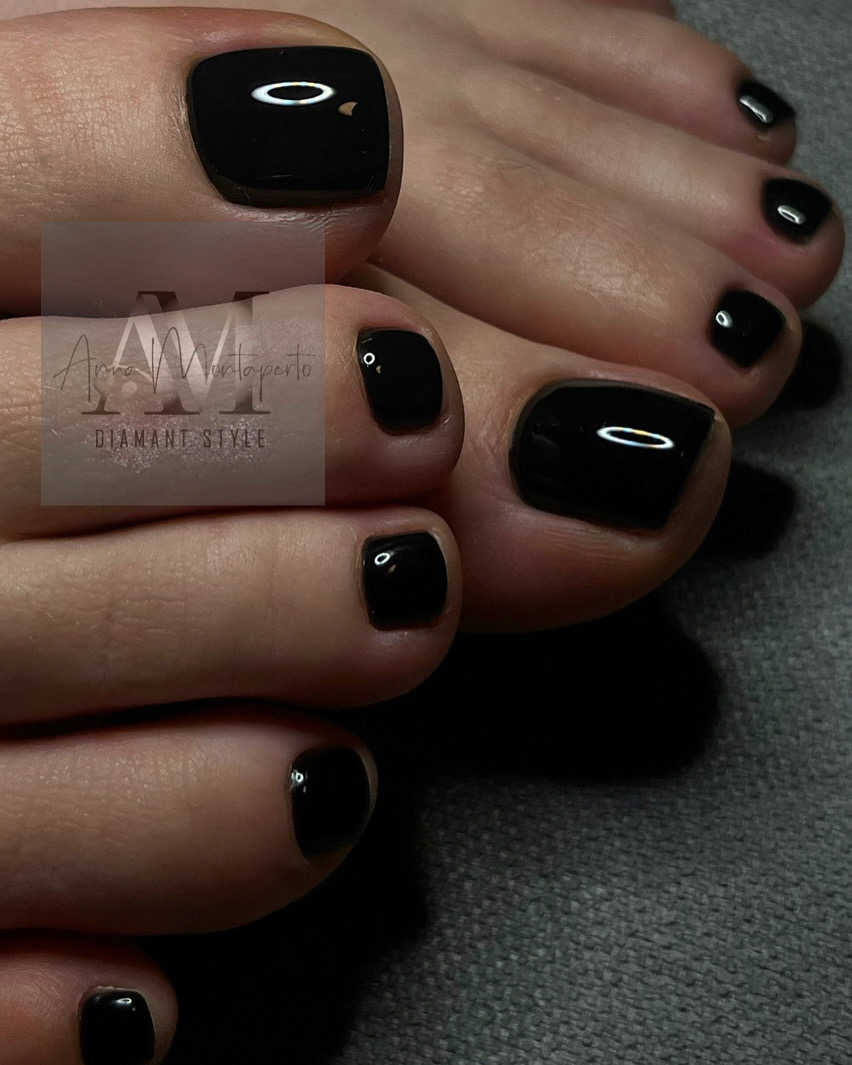 Nahaufnahme von Füßen mit glänzend schwarzem Nagellack auf grauem Hintergrund