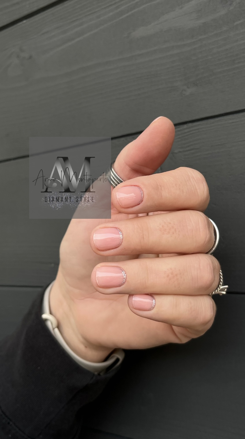 Nahaufnahme einer Hand mit Ringen, die ein Design mit natürlich rosa Nägeln trägt