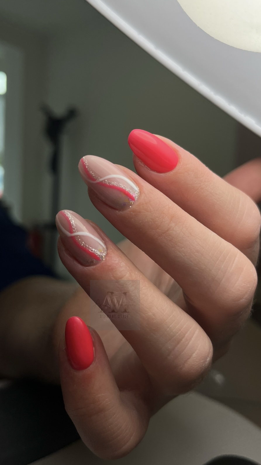 Eine Hand mit auffälligem Nageldesign in Rot und Silberglitzerlinien.
