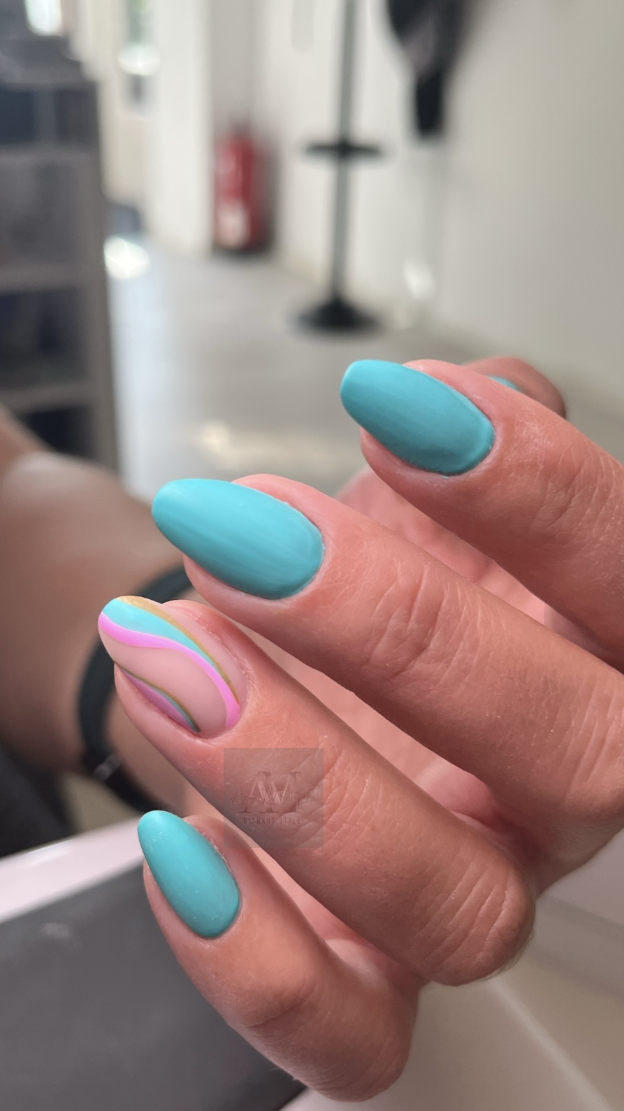 Eine Hand mit türkisfarbenen und einem regenbogenfarbenen Nageldesign.