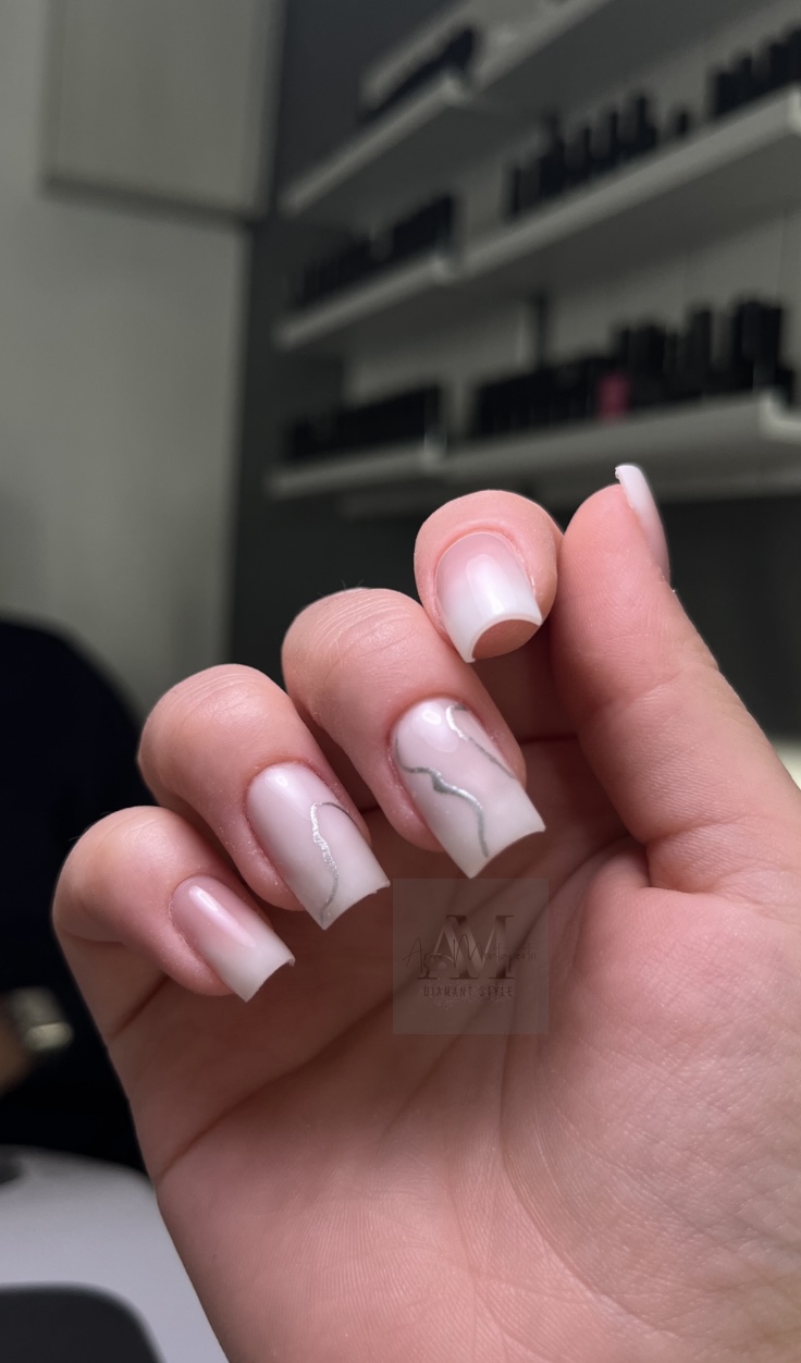 Eine Hand mit elegantem weißen Nageldesign in einem Nagelstudio.