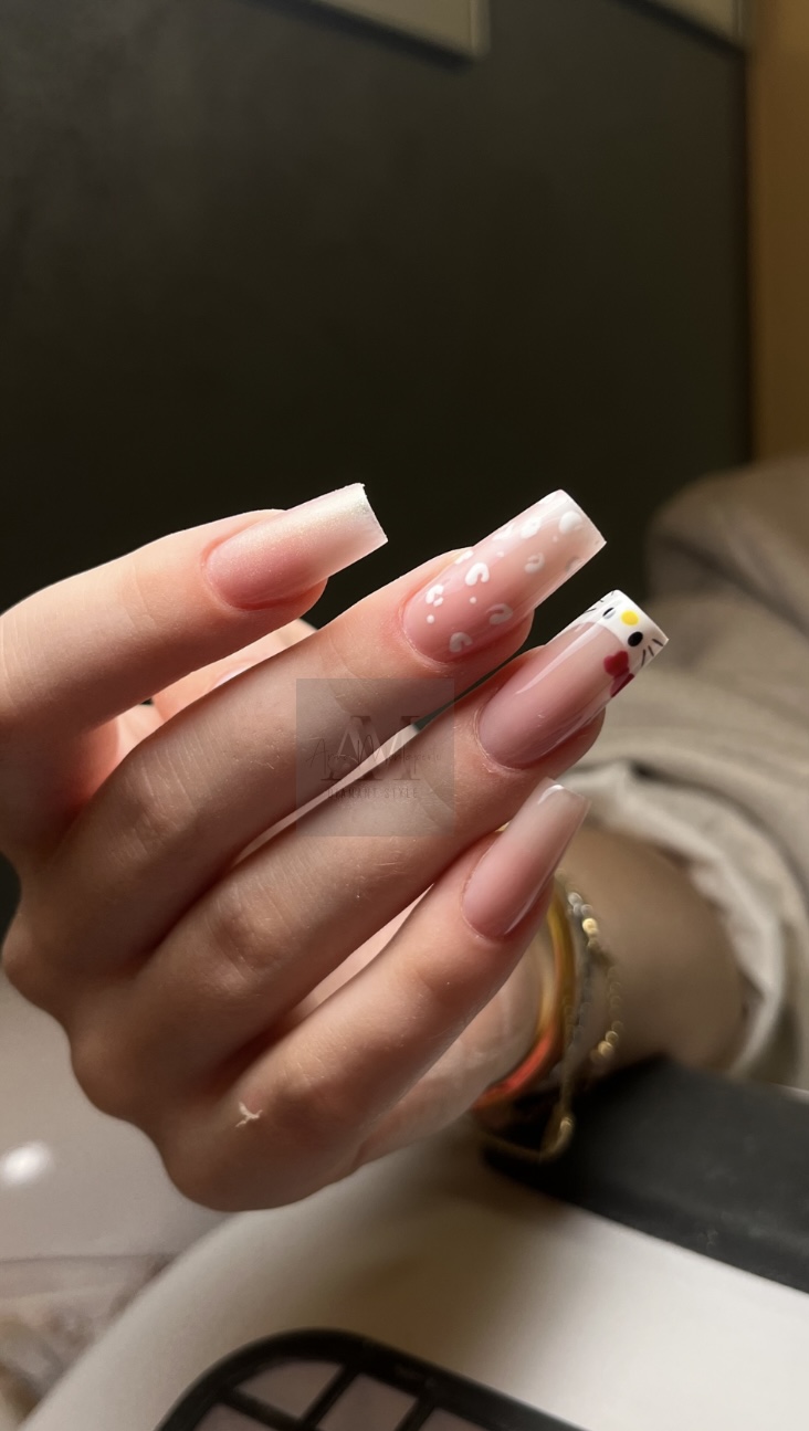 Eine Hand mit langen, rosa Nägeln, verziert mit Punkten und ein Emoji auf einem Nagel.