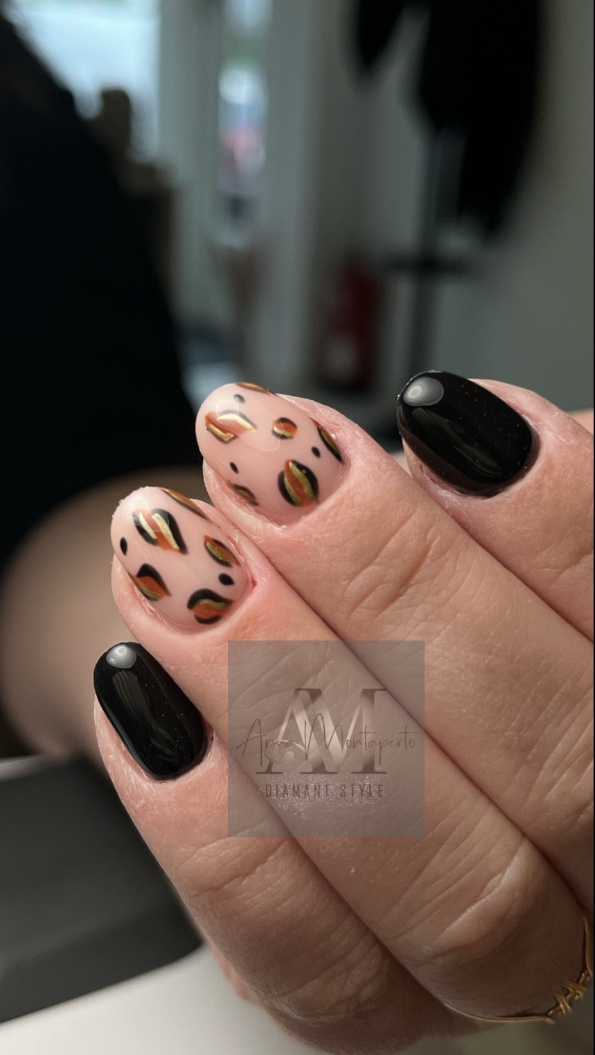 Nahaufnahme einer Hand mit schwarz lackierten Nägeln, einer mit Leopardenmuster.