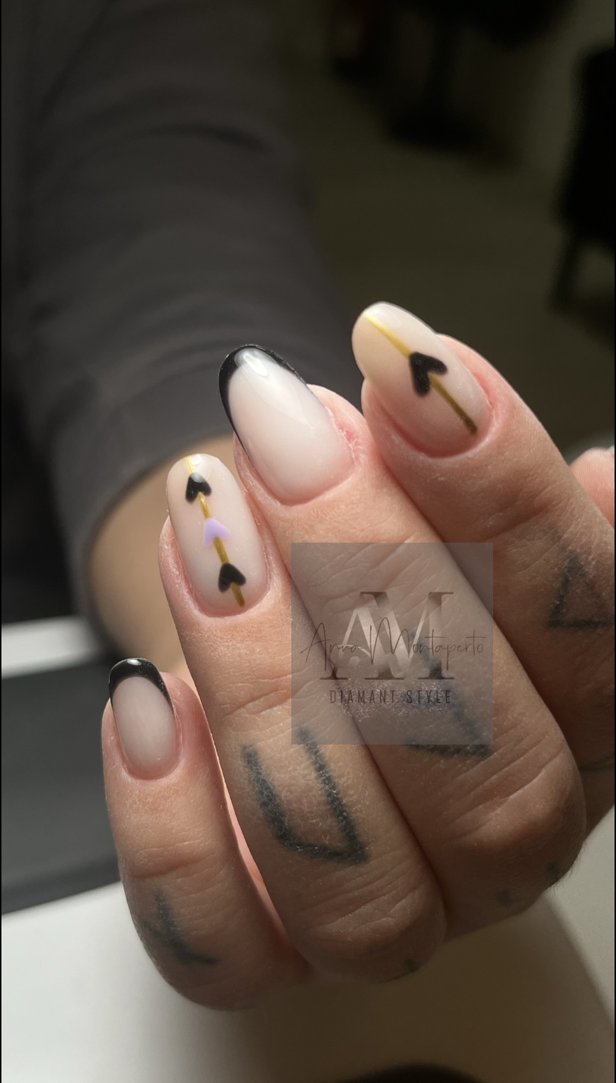 Person showing elegant nails with black tips and arrow designs, neutral colors