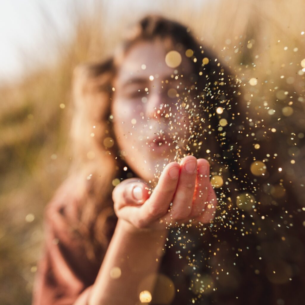 Schöne Aufnahme eines Models, das Glitter aus der Hand bläst